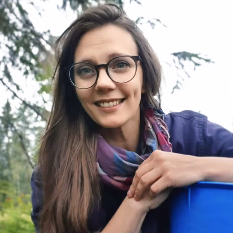 En bild på Amanda Källgren. Hon har långt hår, glasögon och en lila sjal