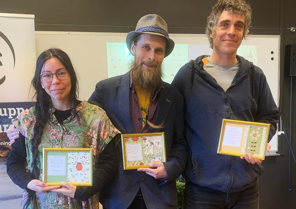 Tre personer står på rad och har precis tagit emot ett diplom i guldram