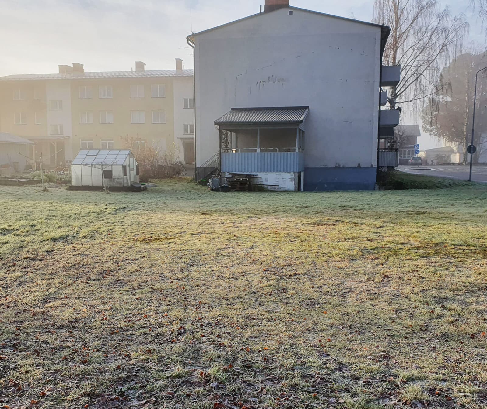 En öde gräsmatta med ett hus i bakgrunden