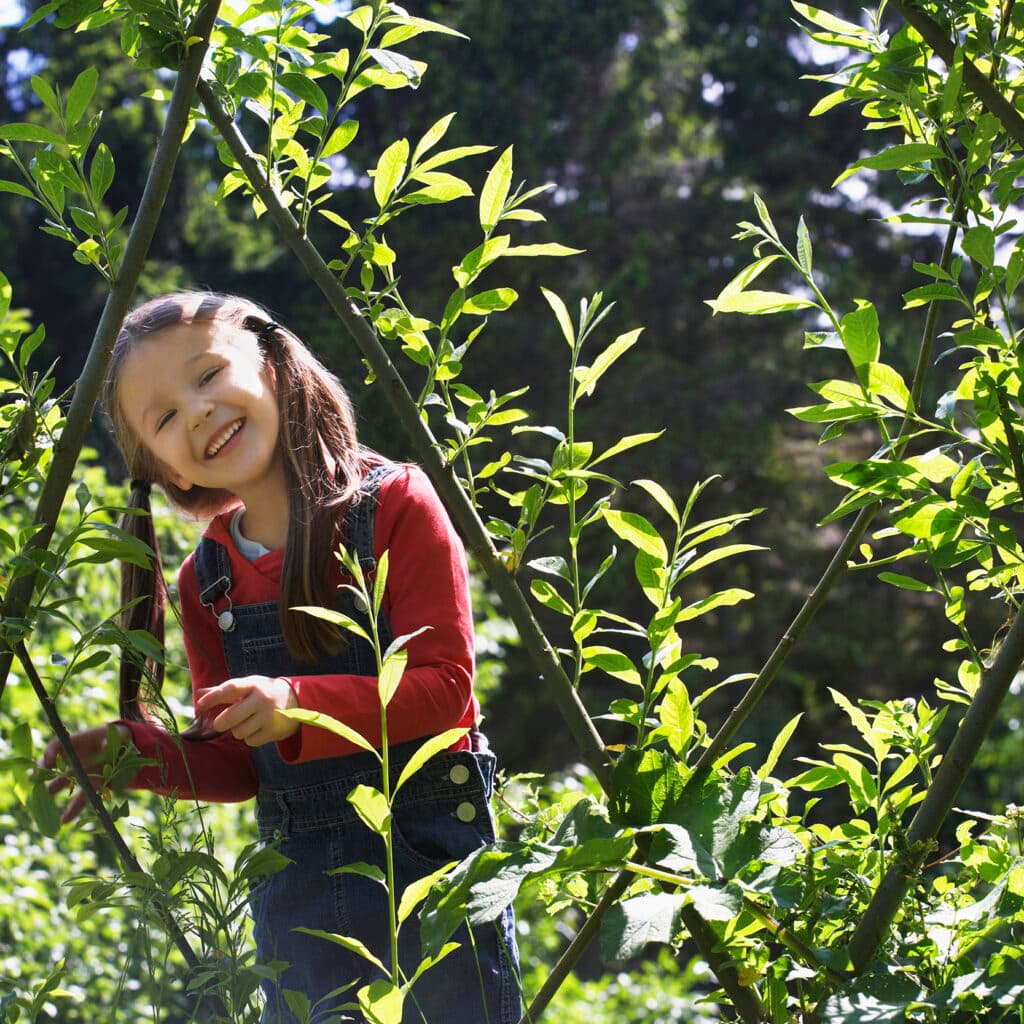 Flicka som står i en grönsaksodling